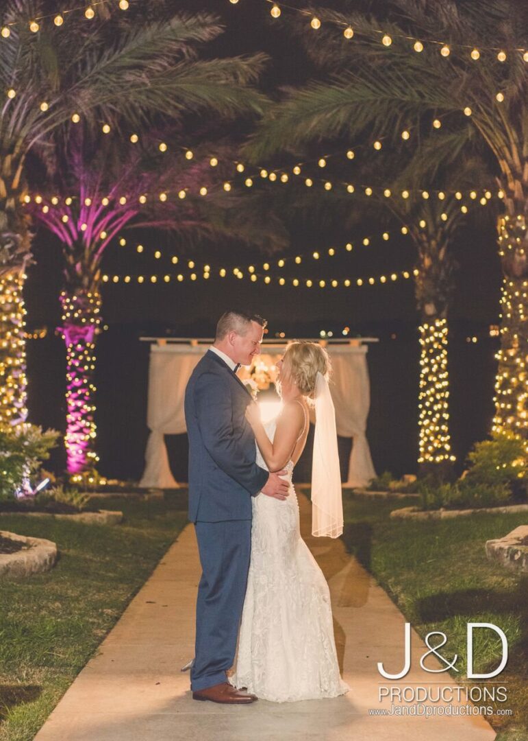 A couple is kissing under the lights at night.