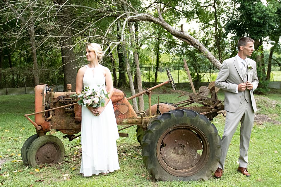 A man and woman standing in front of an old tractor.