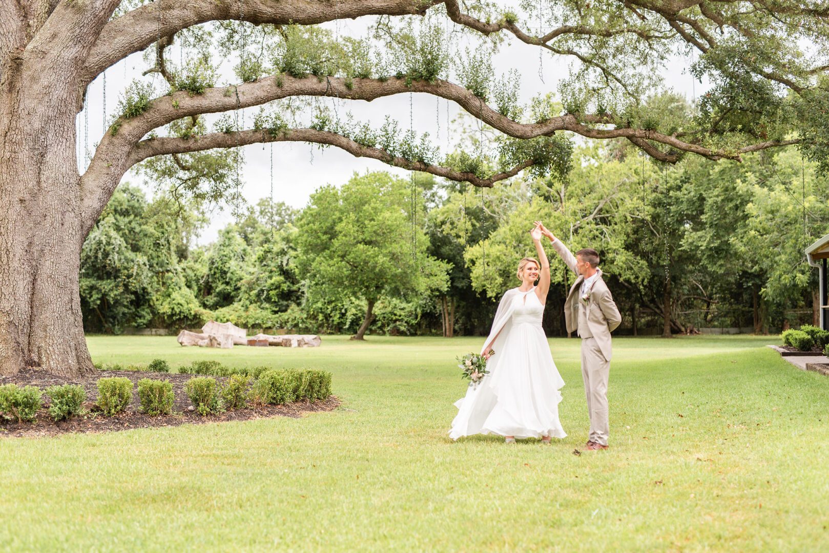 A bride and groom are standing under the tree.