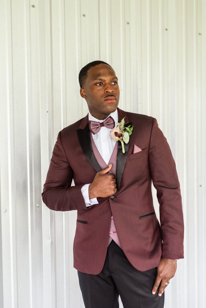 A man in a suit and bow tie standing next to a wall.