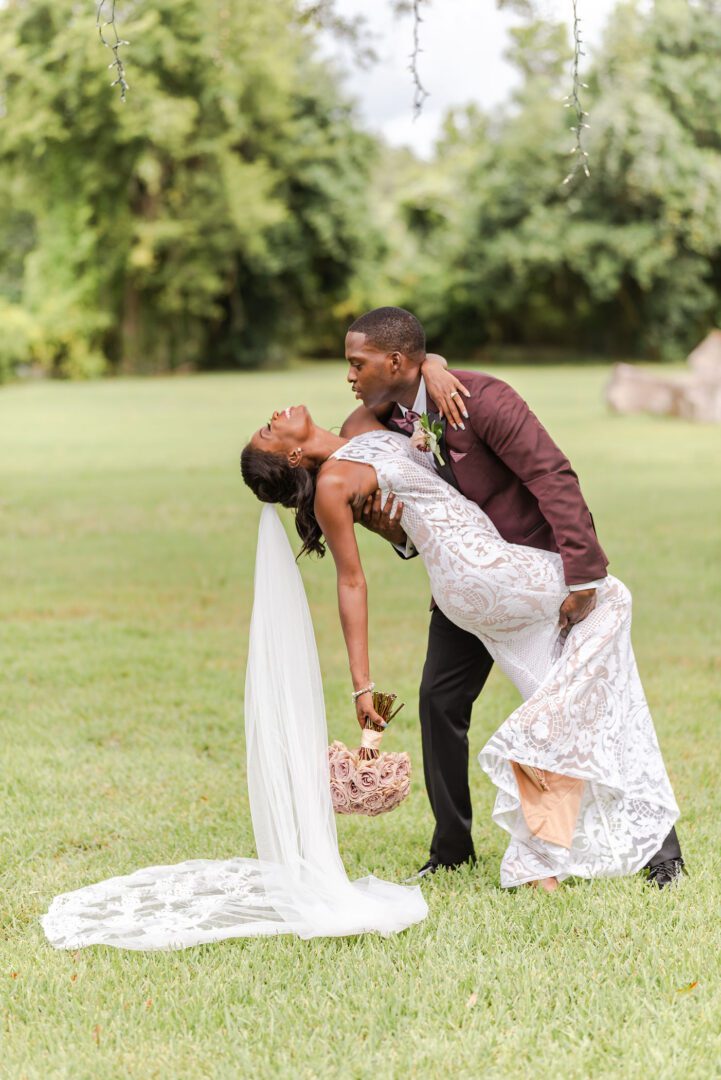 A man and woman are kissing in the grass.