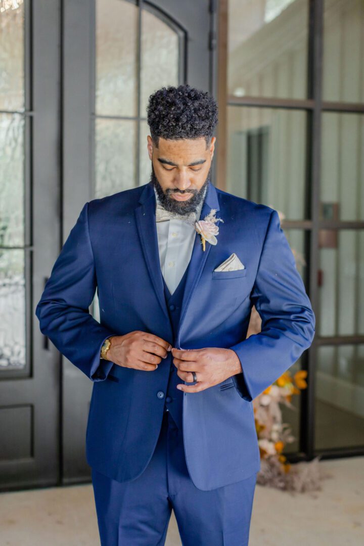 A man in blue suit and white shirt fixing his tie.