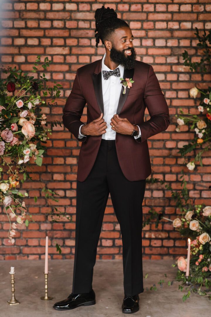 A man in a suit standing next to flowers.