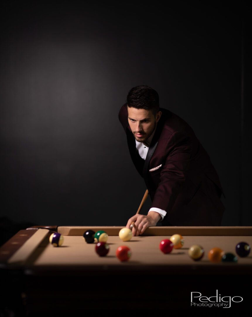 A man in a suit and tie playing pool.