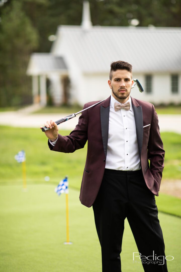 A man in a suit and bow tie holding a golf club.