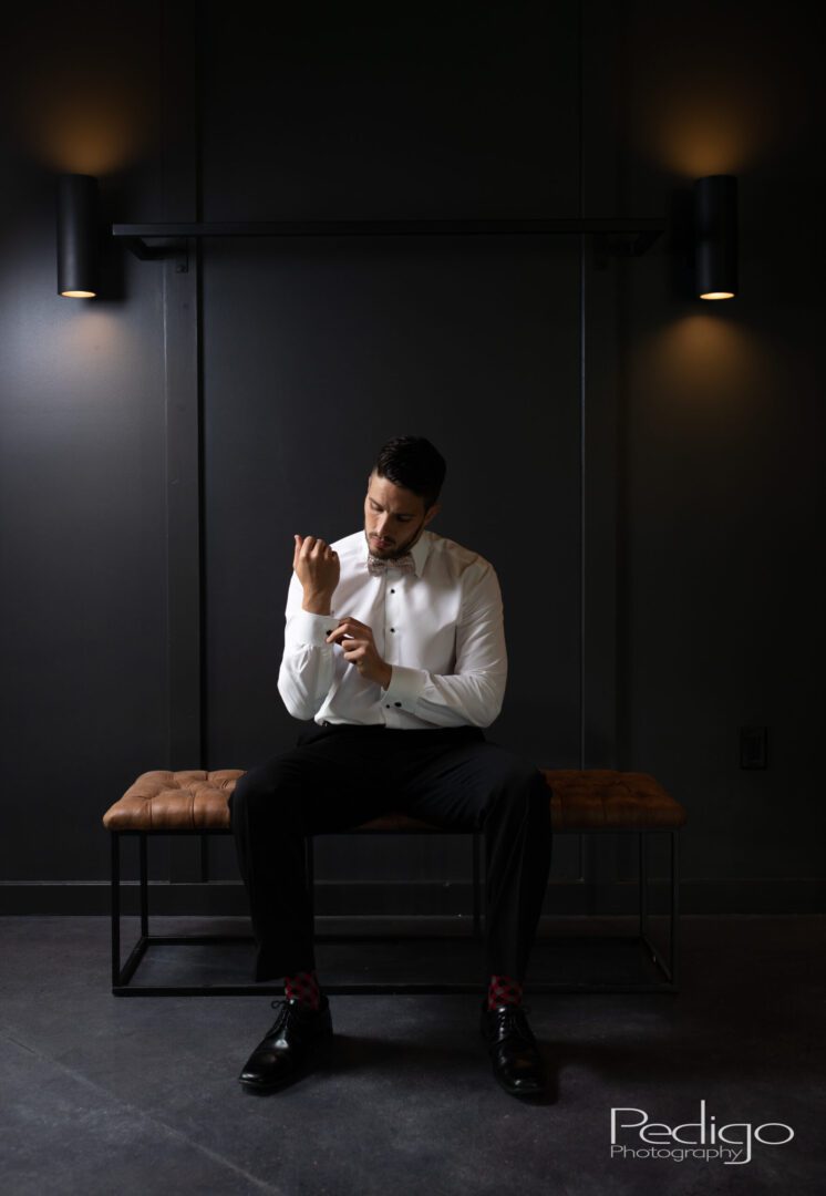 A man sitting on top of a bench in front of a wall.