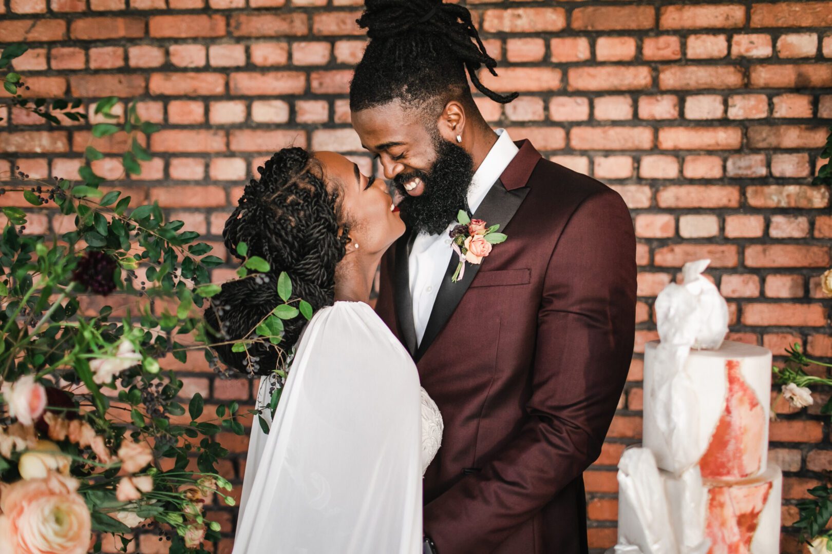 A man and woman kissing in front of a brick wall.