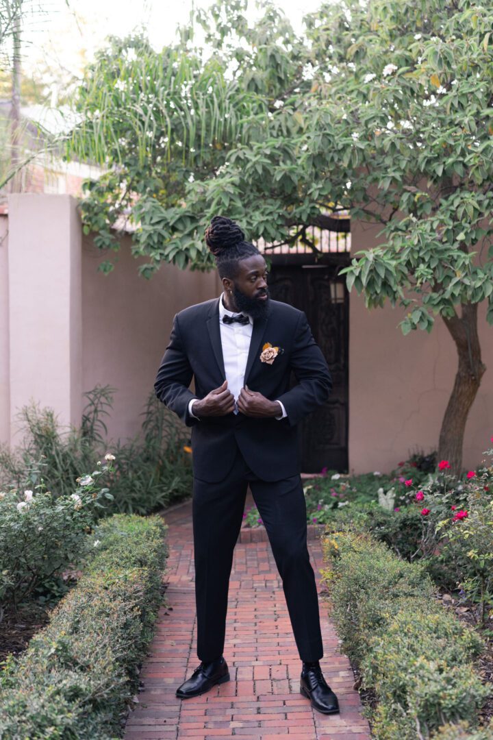 A man in a tuxedo standing outside of a house.