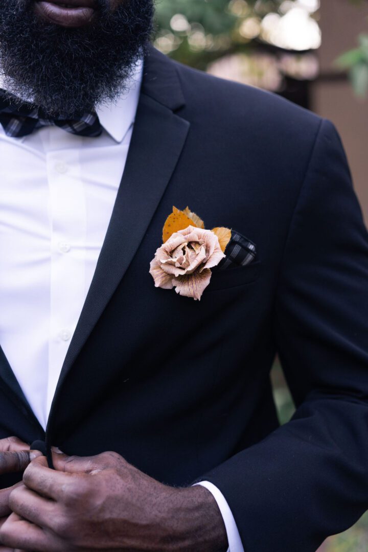 A man in a suit and bow tie with a flower on his lapel.