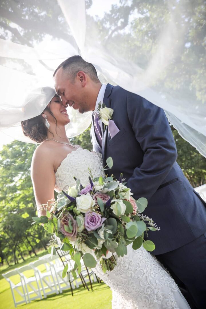 A bride and groom kissing under an umbrella.