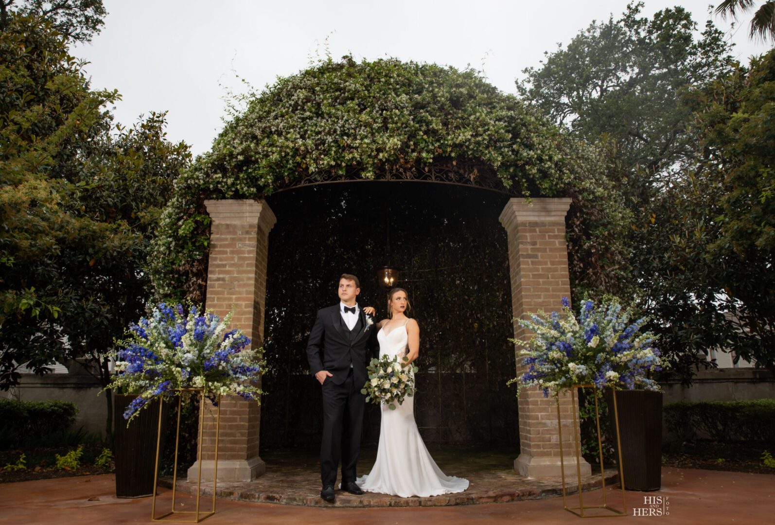 A couple poses for a picture in front of an arch.