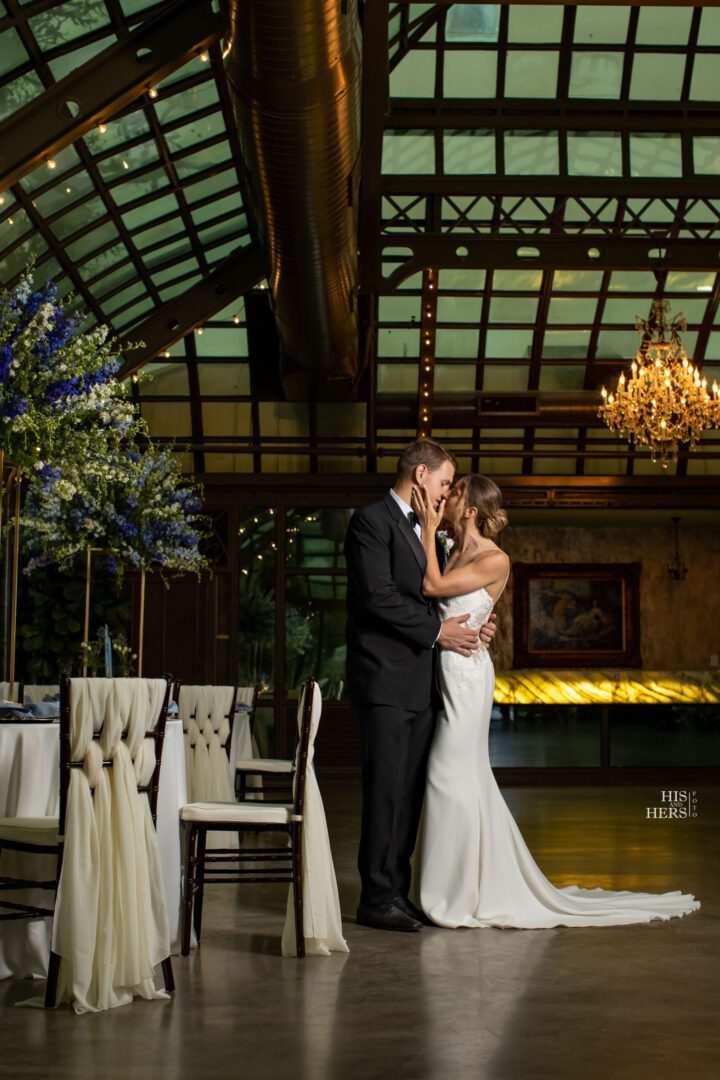 A bride and groom kissing in front of the wedding reception.