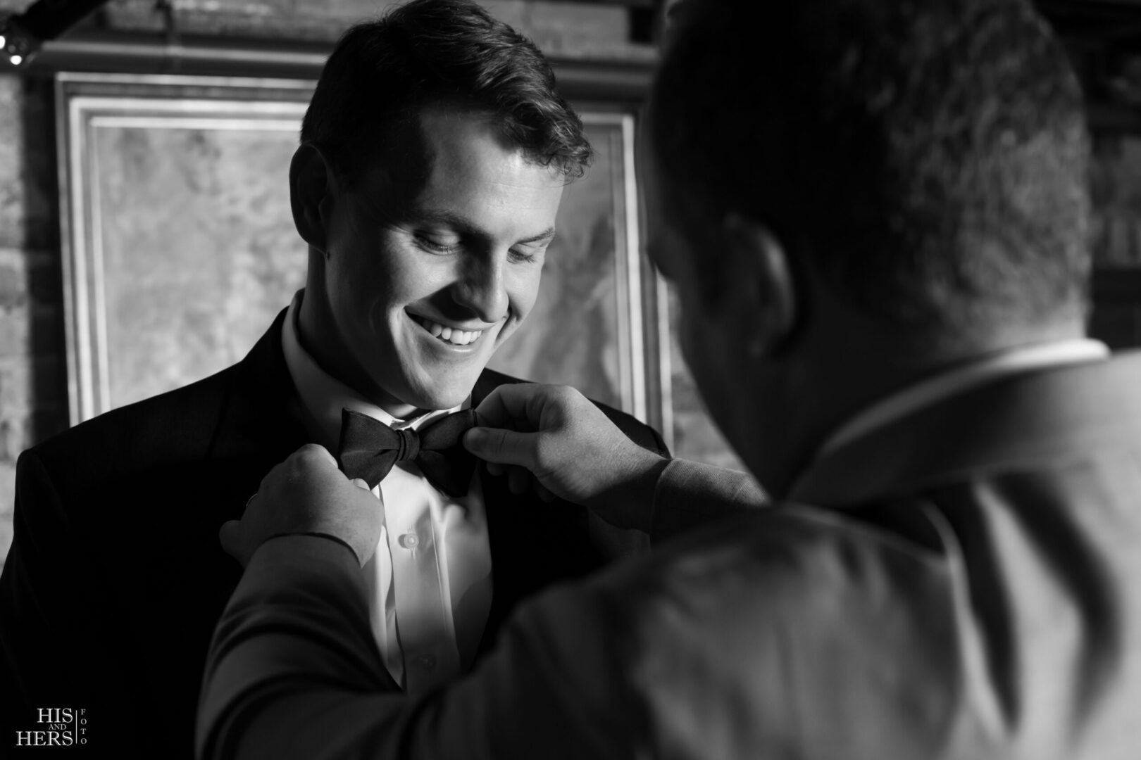 A man fixing another mans bow tie