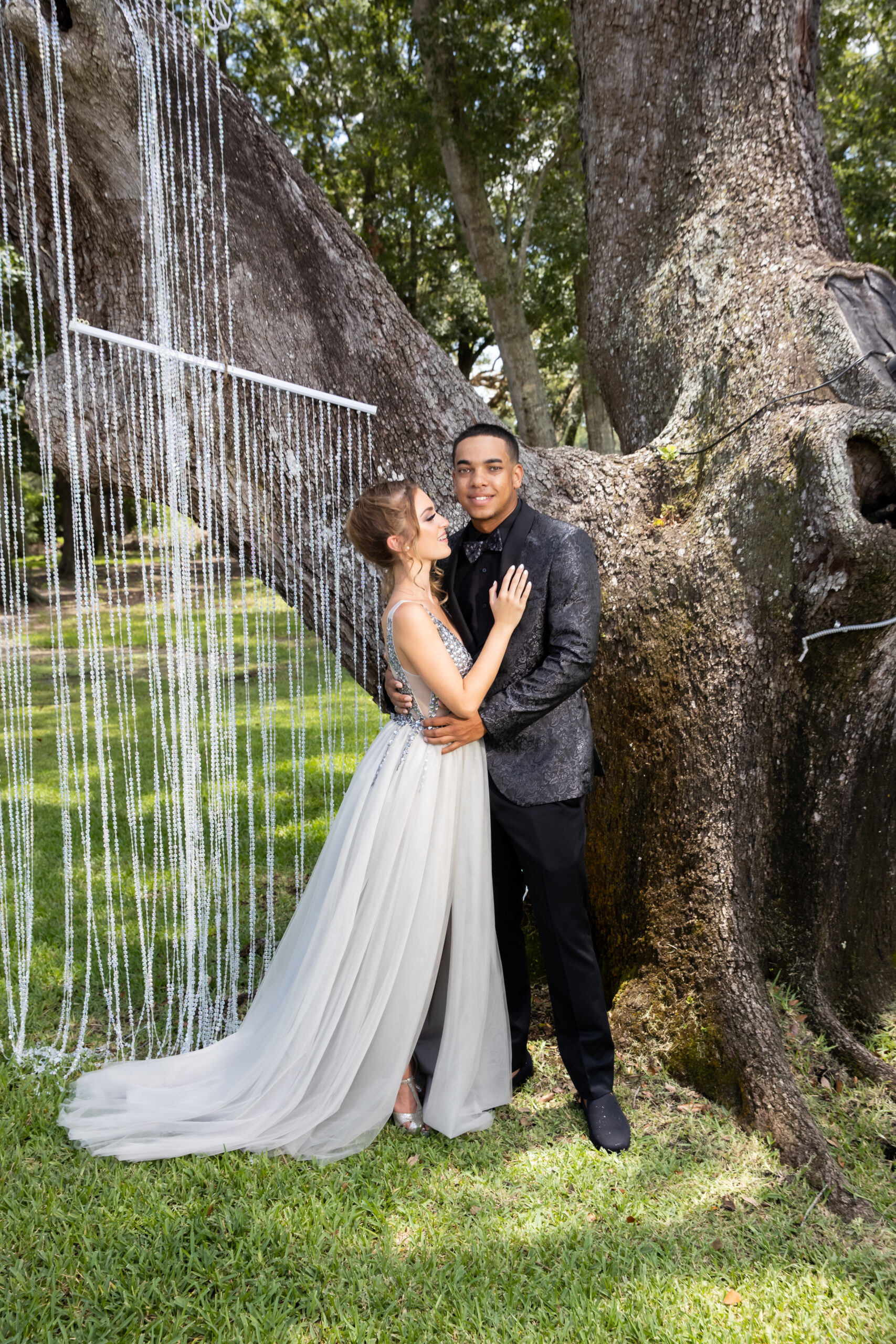 A man and woman posing for a picture in front of a tree.