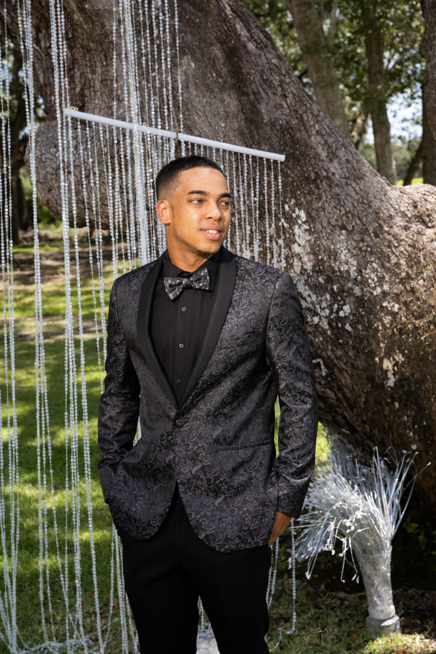 A man in a suit standing next to a tree.