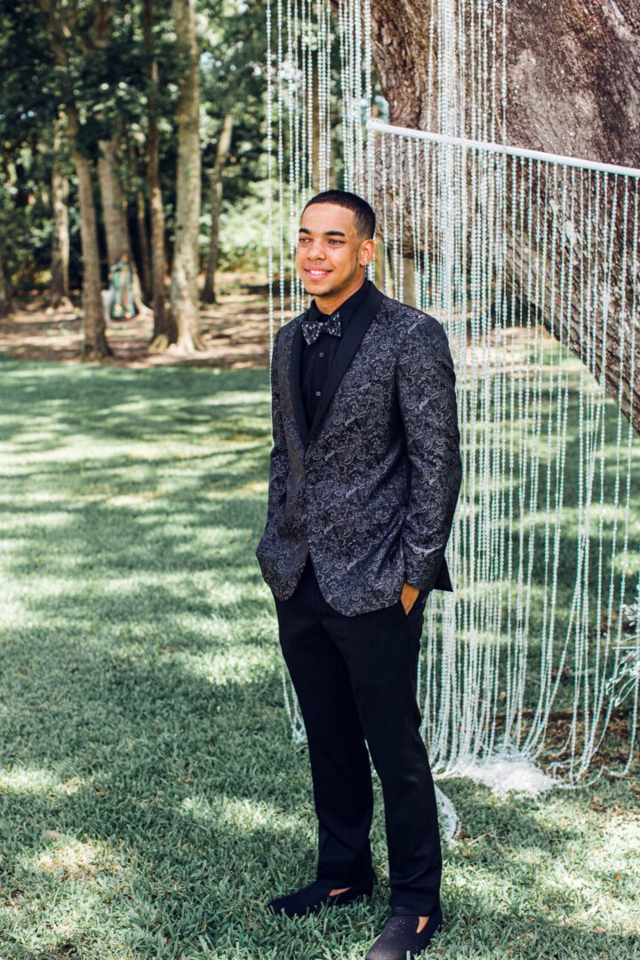 A man in a suit standing next to a waterfall.