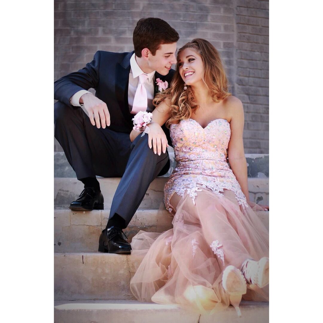 A man and woman sitting on steps in formal wear.