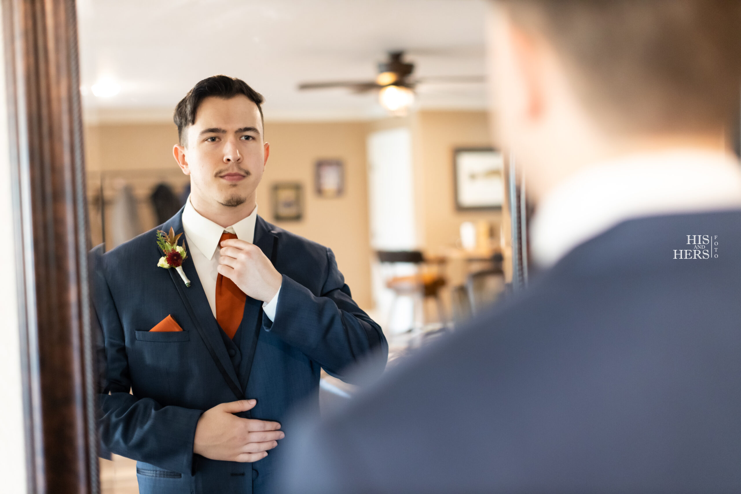 A man in a suit and tie looking at himself in the mirror.