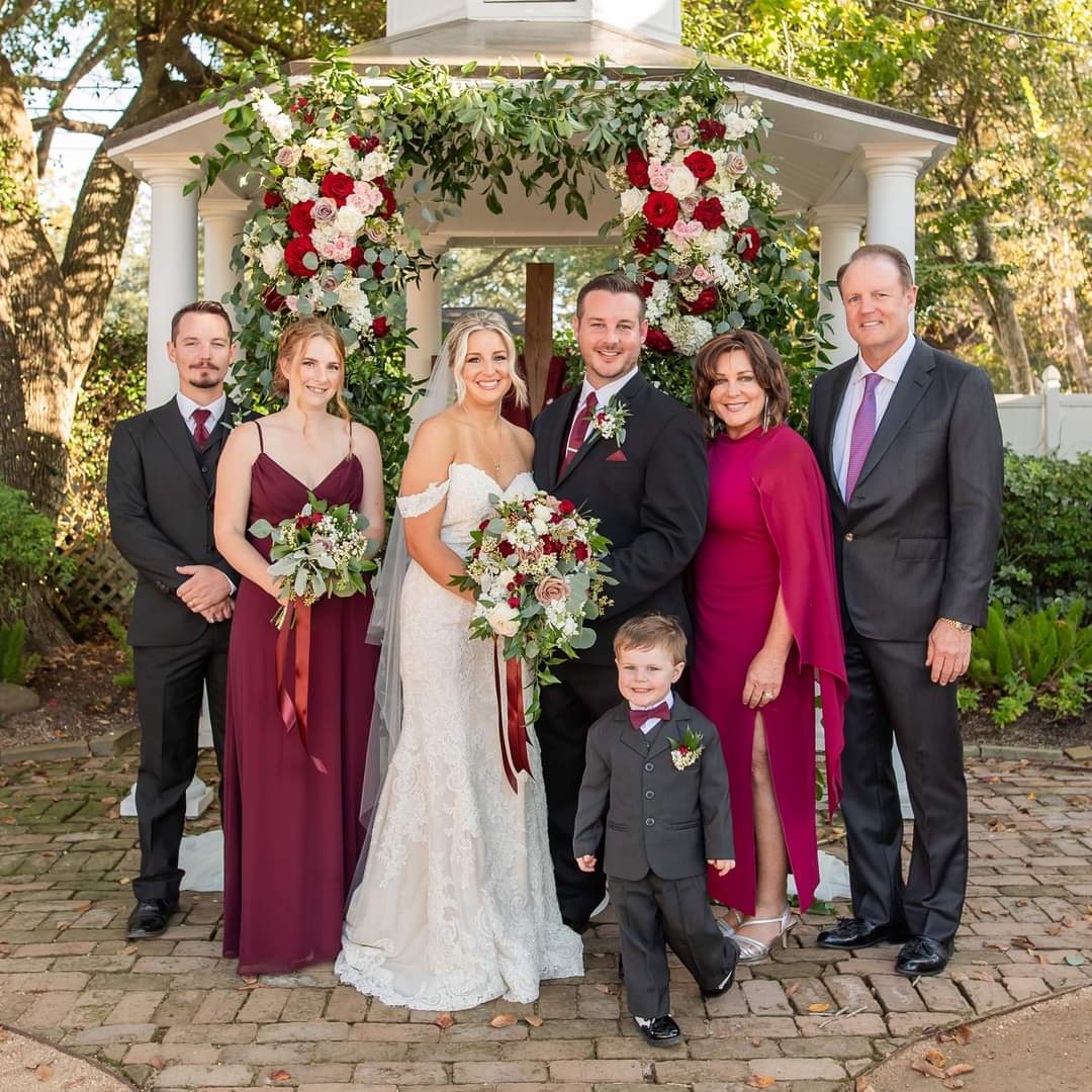 A group of people standing in front of a wedding arch.