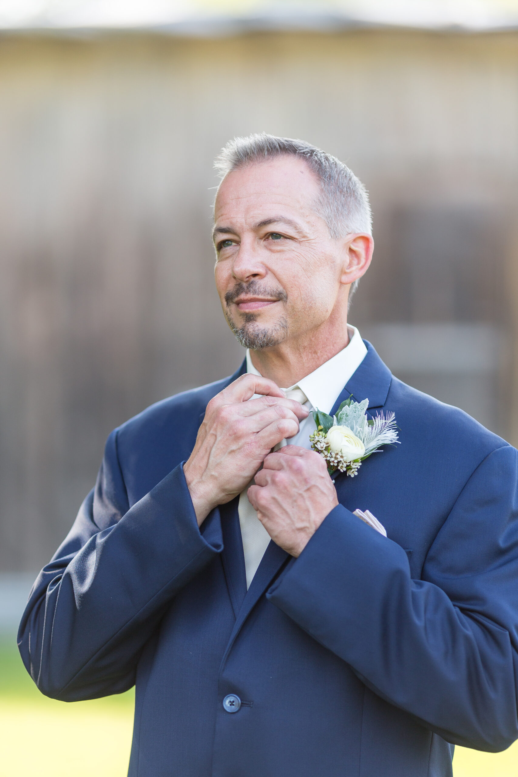 A man in a suit and tie fixing his flower.