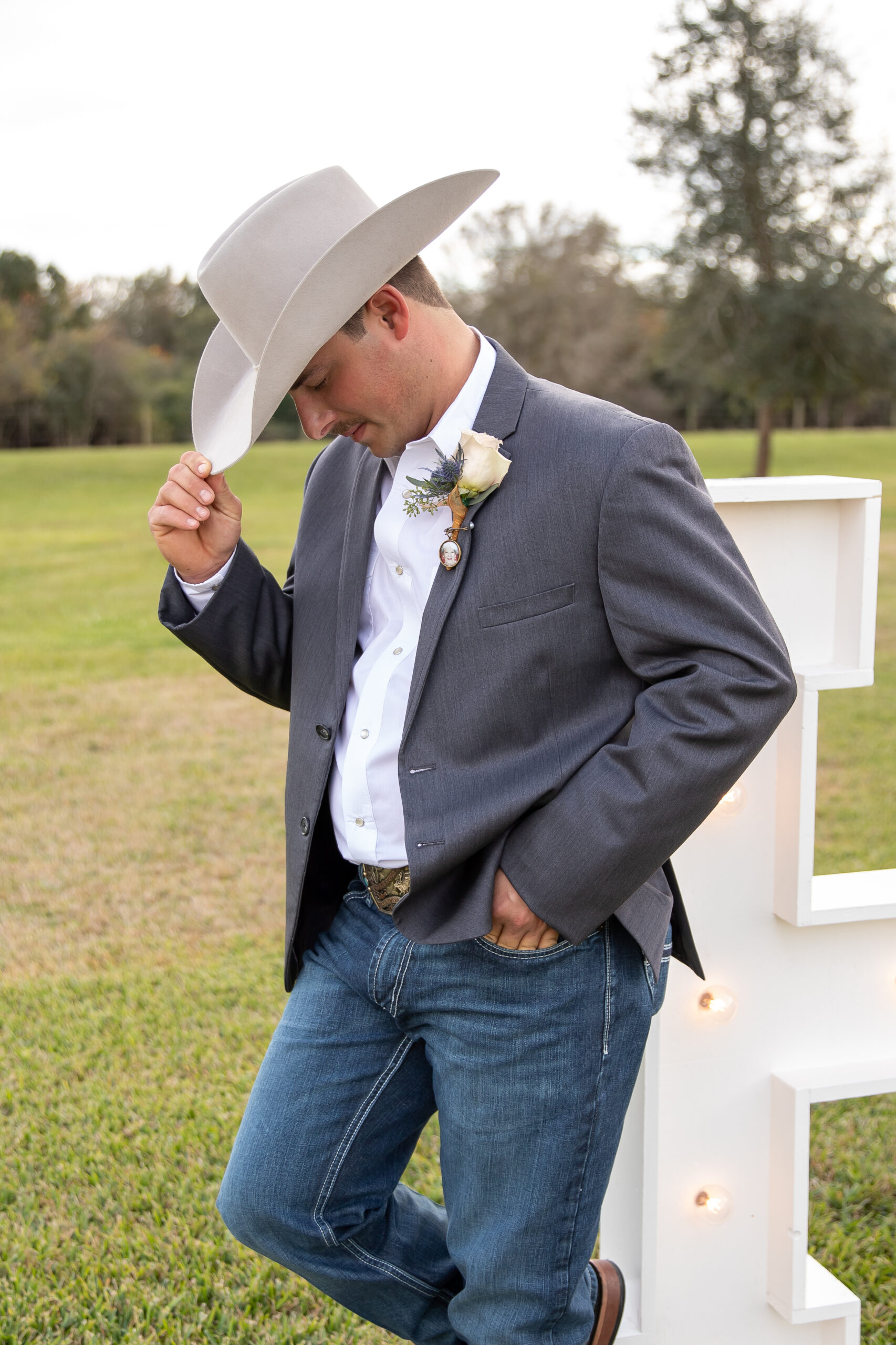 A man in cowboy hat and jacket standing next to white fence.